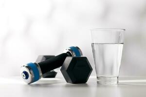Dumbbells and drinking water in a glass after exercising. photo