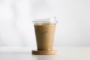 con hielo capuchino en un el plastico vaso en un blanco de madera mesa. foto