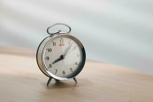 old mechanical alarm clock on wooden table in a living room. photo