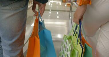 pessoas com compras bolsas indo baixa em escada rolante video