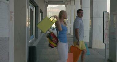 Couple with bags leaving shopping centre video