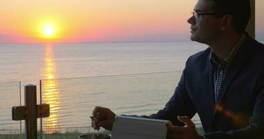 Smoking business man working with touch pad in seaside cafe video