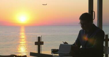 Rauchen Geschäftsmann mit Pad im Strand Cafe beim Sonnenuntergang video