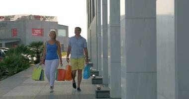alegre casal com compras bolsas caminhando dentro a cidade video