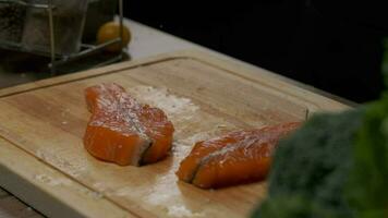 profissional chefe de cozinha prepara vermelho peixe bife para fritando. fechar acima lento movimento. video