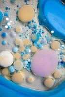 Acrylic paint balls abstract texture. Bright colors fluid, flowing wallpaper design. Purple, blue, pink and yellow liquids mix. photo