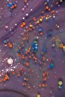 Acrylic paint balls abstract texture. Bright colors fluid, flowing wallpaper design. Purple, blue, pink and yellow liquids mix. photo