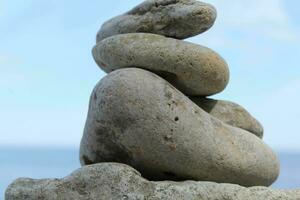 rocas apilado uno en parte superior de otro en el antecedentes de el mar foto