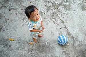 pequeño chico jugando pelota en el yarda foto