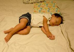 niño chico dormido bien en hotel cama foto