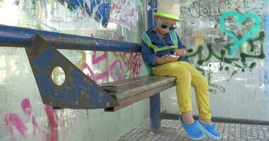 Child using smart phone on grungy bus stop video