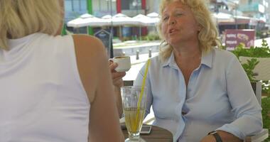 mayor mujer hablando y teniendo bebidas en calle café video