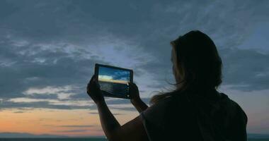 kvinna med vaddera framställning foton av hav och himmel i de skymning video