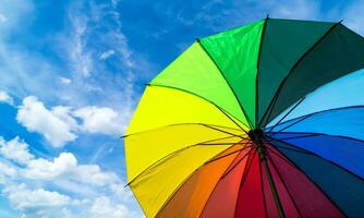 Colorful rainbow umbrella on blue sky background. LGBT, Pride Month, diversity, Sunprotect Concept. photo