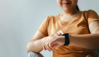 joven mujer mirando y utilizando un reloj inteligente, hembra sentado en el sofá comprobación su reloj inteligente. foto