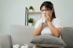 Young woman got a nose allergy sneezing sitting on the sofa at home.  Flu, Influenza, Sick, Fever, Illness. Healthcare and medical concept. photo