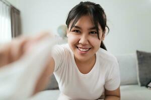 Happy woman cleaning the camera lens, screen looking at the camera in the living room at home. photo