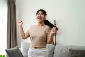 joven mujer escucha a música con auricular y danza en el vivo habitación a hogar. foto