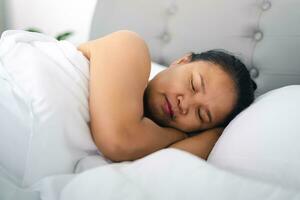 Mature woman sleeping on the white bed at home. photo