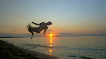 atleta fazendo acrobático truques em a de praia às pôr do sol video