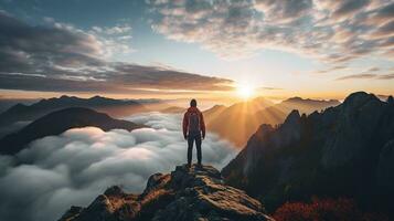 a man on top of a mountain peak with view of clouds and sunrise photo