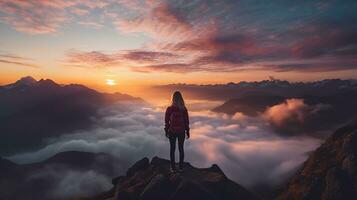 a woman on top of a mountain peak with view of clouds and sunrise photo
