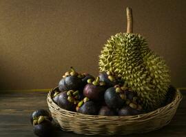 a basket of mangosteen and durian on a wooden table photo