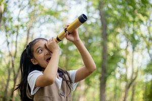 Happy Little Asian girls looking ahead and smiling child with the binoculars in the park. Travel and adventure concept. Freedom, vacation photo