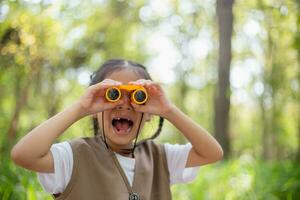 Happy Little Asian girls looking ahead and smiling child with the binoculars in the park. Travel and adventure concept. Freedom, vacation photo