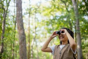 Happy Little Asian girls looking ahead and smiling child with the binoculars in the park. Travel and adventure concept. Freedom, vacation photo