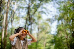 Happy Little Asian girls looking ahead and smiling child with the binoculars in the park. Travel and adventure concept. Freedom, vacation photo