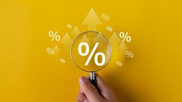 Interest rate and dividend concept. magnifying glasses and percentage symbols and an up arrow, interest rates continue to increase, and return on stocks and mutual funds. on yellow background photo