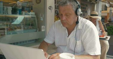 homem dentro fones de ouvido digitando dentro computador portátil video