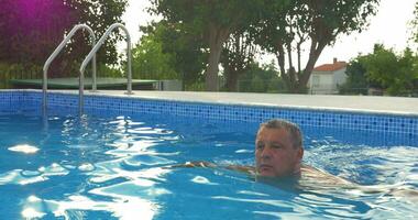 maduro hombre relajante con nadando en el piscina video