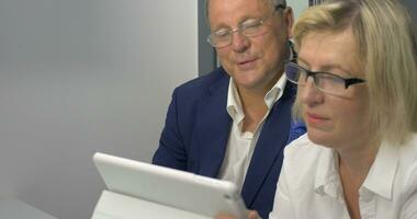 maduro hombre y mujer haciendo negocio con tableta ordenador personal video