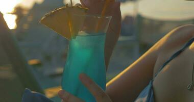 Jeune femme ayant cocktail sur plage à le coucher du soleil video