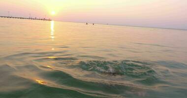 poco bambino nel occhiali avendo divertimento nel mare durante tramonto video