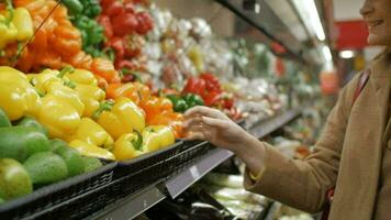 Happy girl buying fresh yellow peppers in grocery video