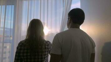 Young couple looking at big city through the window video
