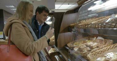 homem e mulher comprando delicioso pão dentro a fazer compras video