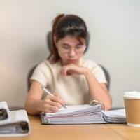 Asian woman reading financial report, female businesswoman sign contract or writing documents  paper at home or office late night. Overworked, work hard and business concept photo