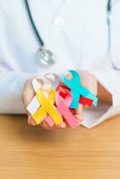 World cancer day, February 4. Doctor hold colorful ribbons, blue, yellow, red, green, white, pink and grey for supporting people living and illness. Health, Medical, awareness and Insurance concept photo