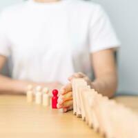 Hand stop falling wood domino blocks on table. Crisis, fall Business, Risk management, Economic recession, Strategy and solutions concept photo