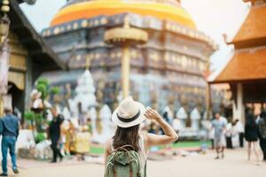 Young asian woman traveler in white dress with hat and bag traveling in Wat Phra That Lampang Luang, Tourist visit at Lampang, Thailand.. Asia Travel, Vacation and summer holiday concept photo