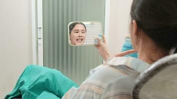 asiático masculino dentista explica ortodoncia cuidado y blanqueo a un joven hembra paciente con implante dentadura color sombra en dental clínica, dientes higiene, y profesional cuidado de la salud médico en un hospital. video