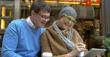 gelukkig paar gebruik makend van digitaal tablet Bij straat cafe video