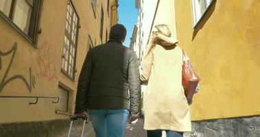 couple de touristes avec roll-on sac en marchant dans vieux rue video