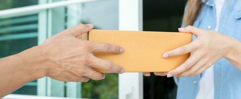 woman receives boxes parcel from courier in front house. Delivery man send deliver express. online shopping, paper containers, takeaway, postman, delivery service, packages photo