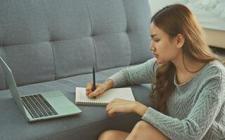 Asian woman sitting on floor holding pen, writing, working from home, noting, writing down, housewife planning week, writing to-do list, student preparing university admissions. photo