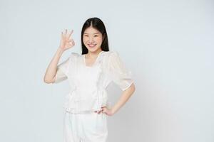 Portrait of young woman smiling and showing ok sign isolated on white background. photo